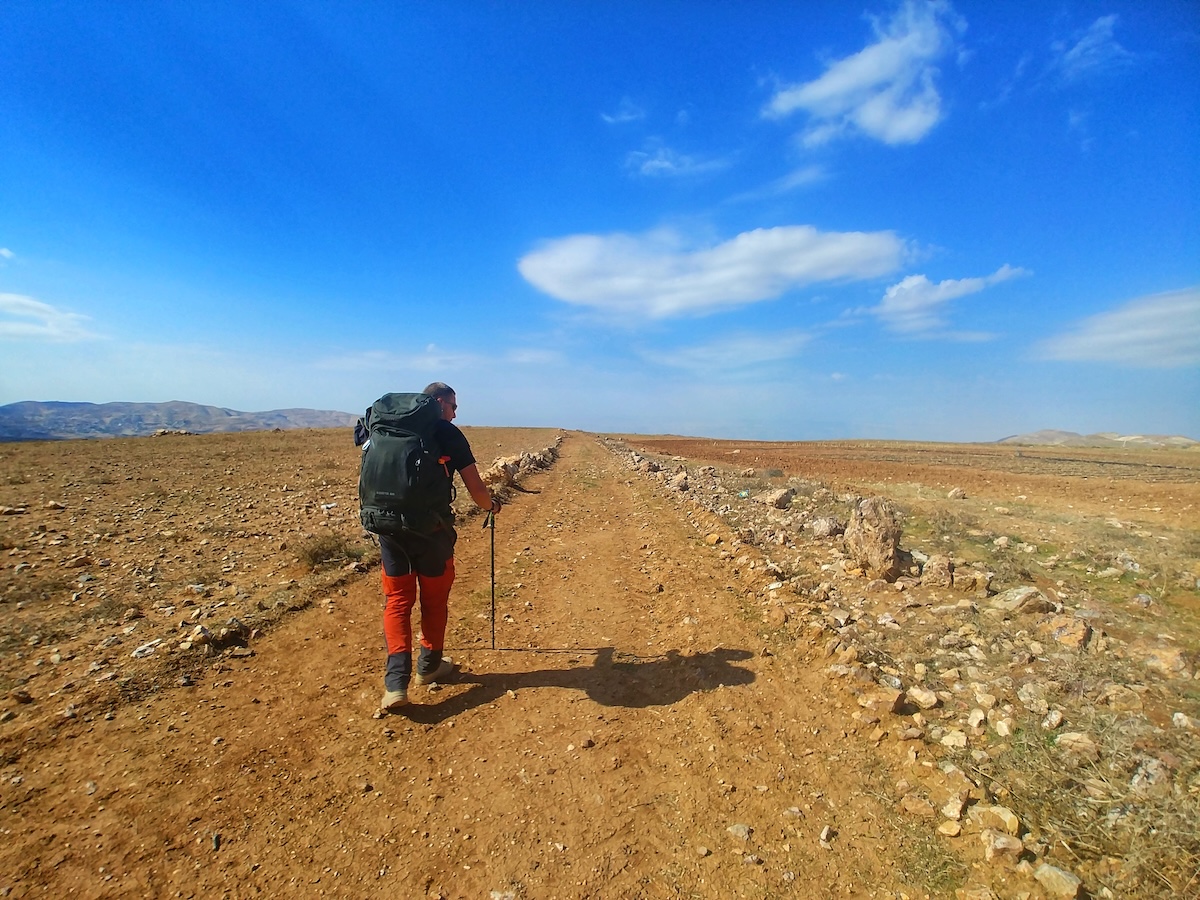 Marco cammina con lo zaino nel deserto aperto della Giordania durante il Jordan Trail